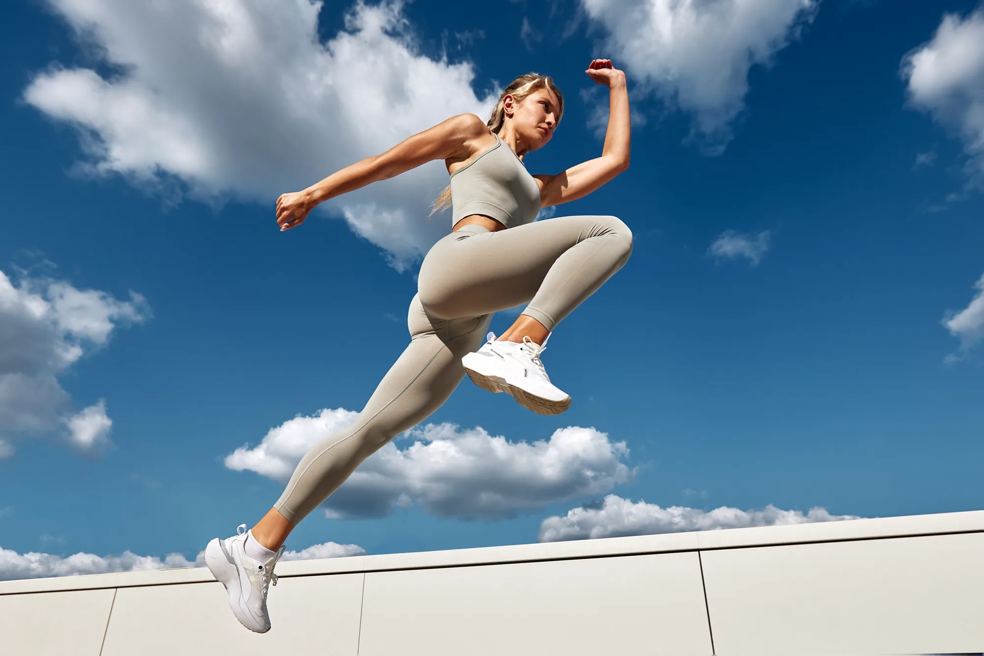 A woman leaping mid-run against a blue sky