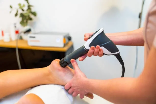 A shockwave therapy applicator held against a patient's foot